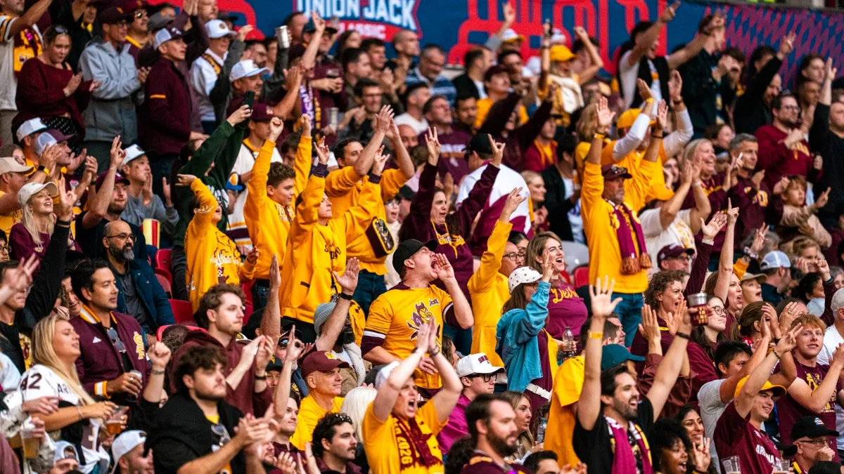 A group of Sun Devil fans wearing gold shirts cheer in Wembley Stadium