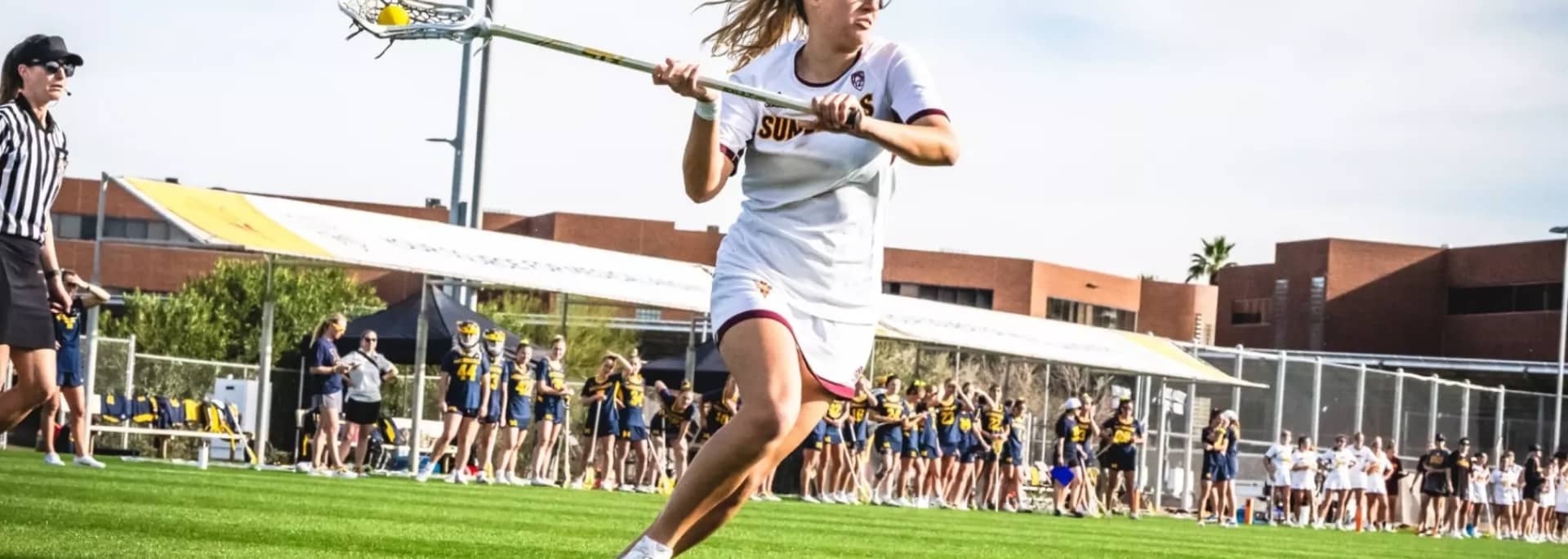 An ASU lacrosse player is shown running in the middle of a match.