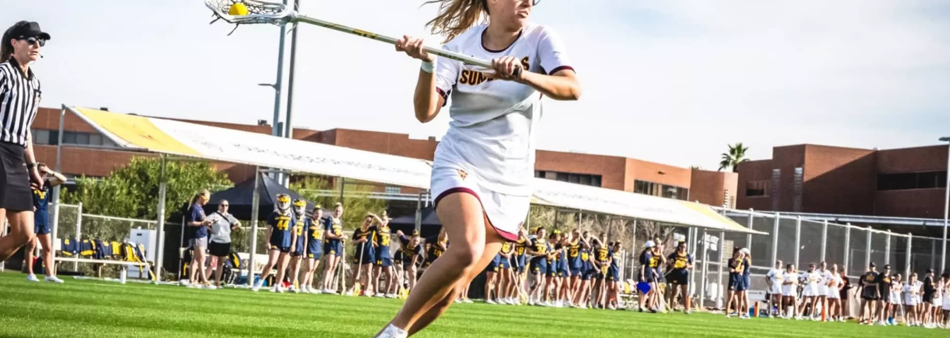 Sun Devil Lacrosse player with stick running in field