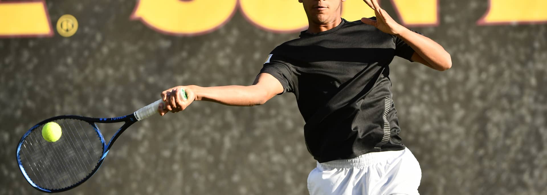 A Sun Devil tennis player hitting a tennis ball in the air.