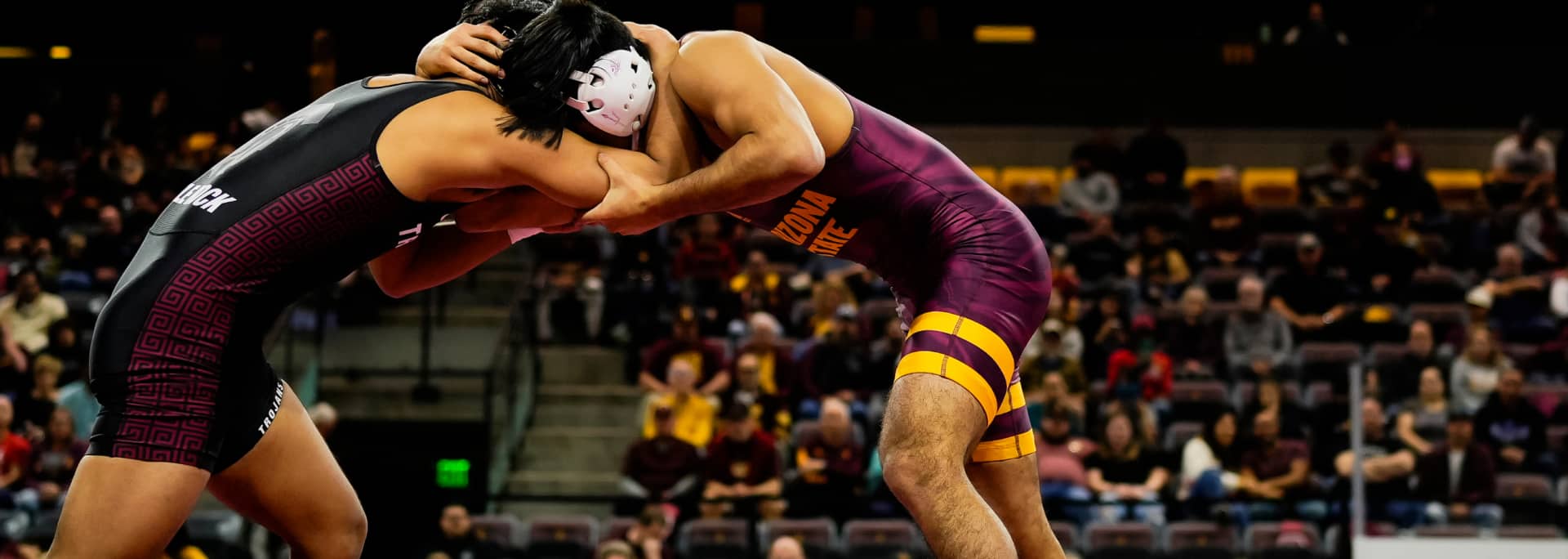 Two student athletes wrestling. One is an ASU wrestler, wearing maroon and gold.