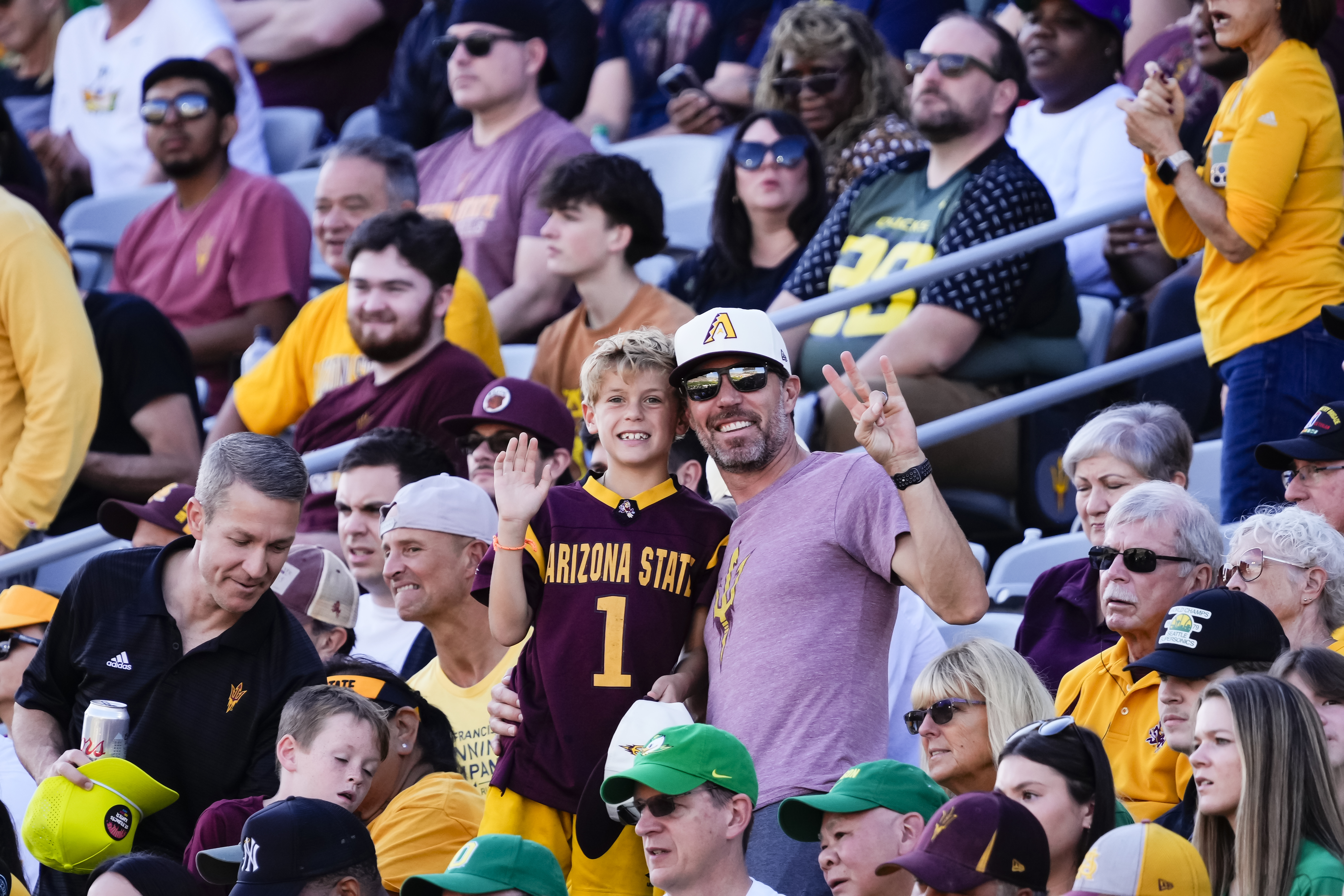 Father and son smiling for a photo in the football stadium stands