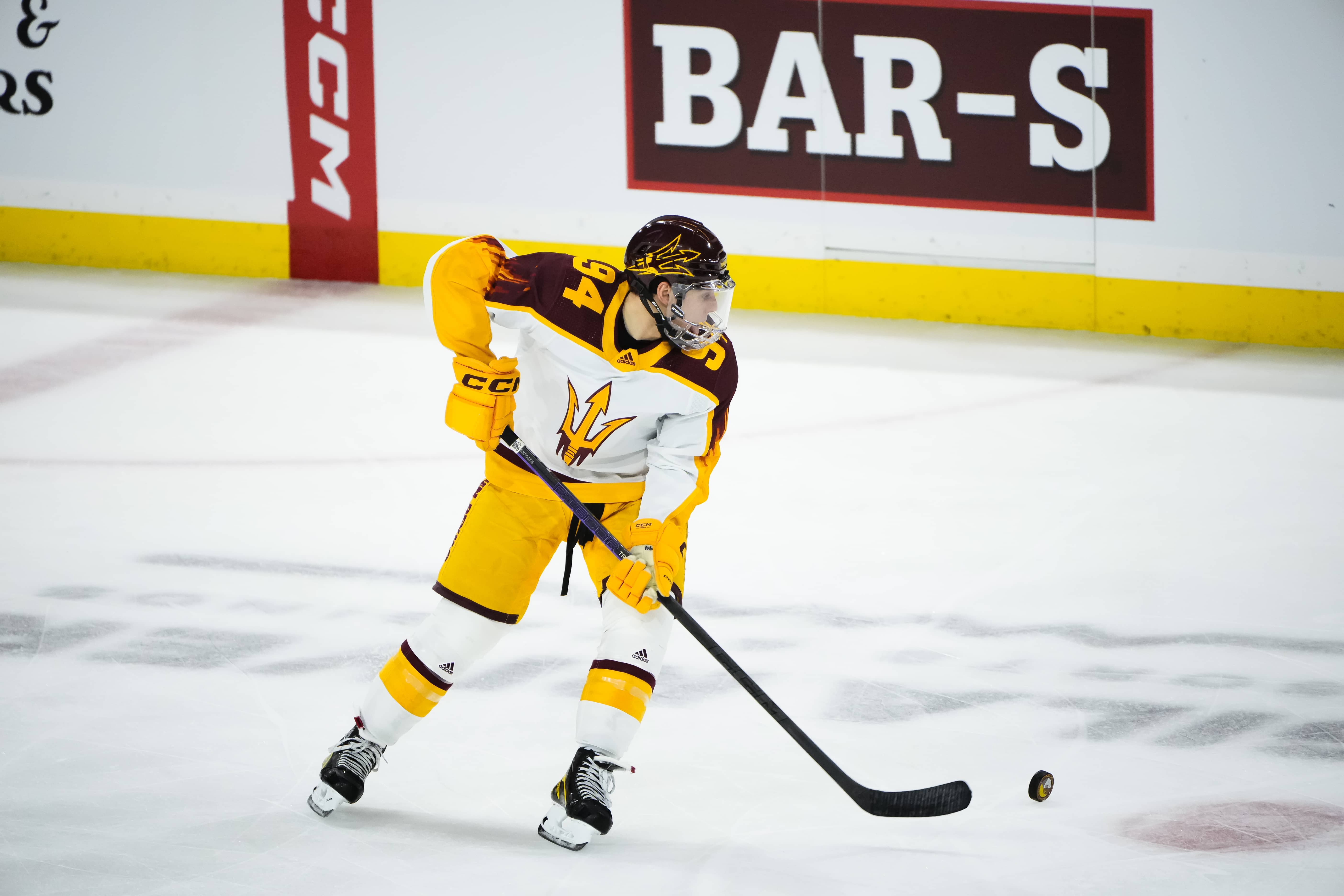 ASU hockey athlete hitting puck across the ice 