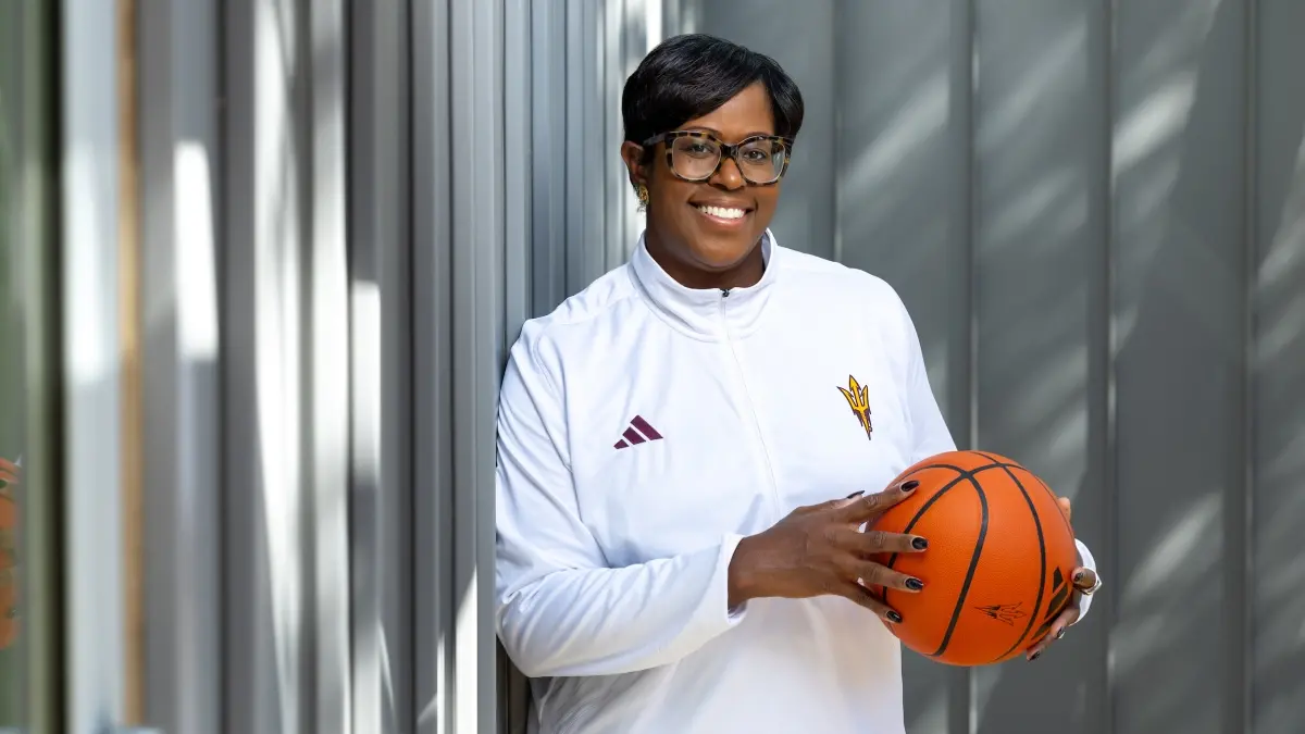 Portrait of a Black woman wearing a white track suit jacket and glasses holding a basketball Portrait of a Black woman wearing a white track suit jacket and glasses holding a basketball