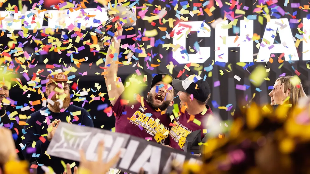 Two football players cheer in celebration as confetti falls.