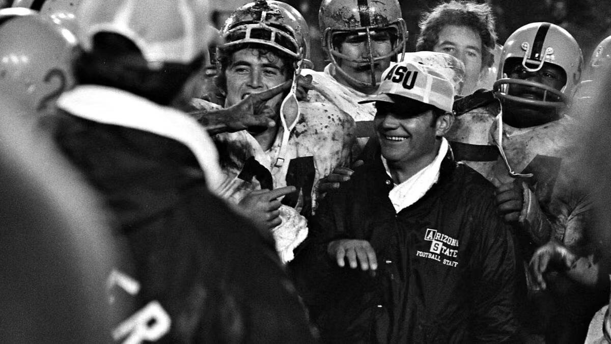 Football coach Frank Kush smiling with team