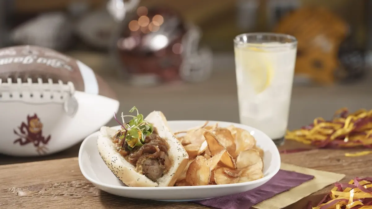 plate of food, glass of lemonade and a football with a ASU Sparky logo on it