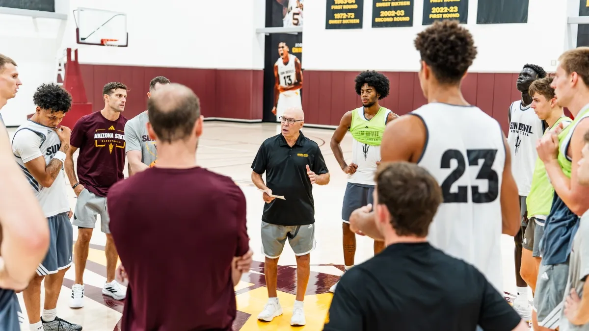Coach speaking to basketball players on a court.