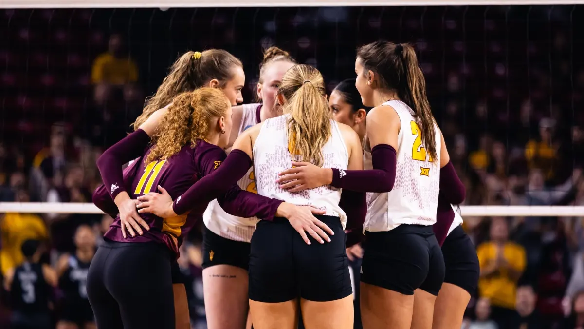 Volleyball players huddle together.