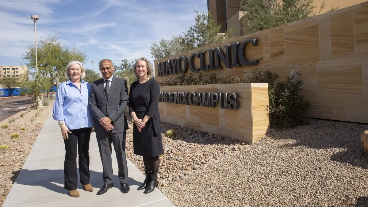 Three people stand outside next to a large sign that reads "Mayo Clinic Phoenix campus." Three people stand outside next to a large sign that reads "Mayo Clinic Phoenix campus."