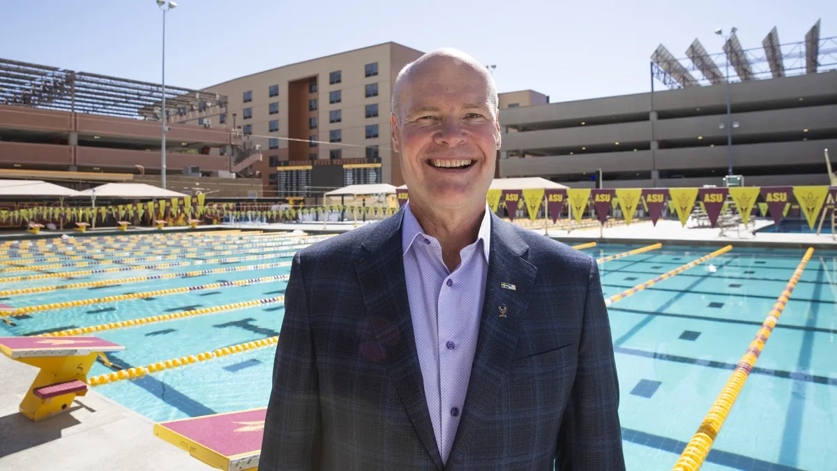 Mikael Örn poses in front of a large swimming pool.