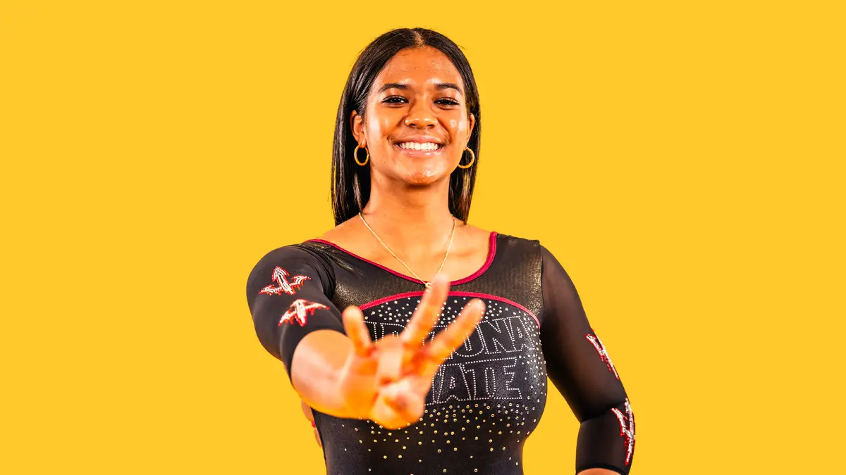 Gymnastics signee Safia poses in front of a gold backdrop. Gymnastics signee Safia poses in front of a gold backdrop.