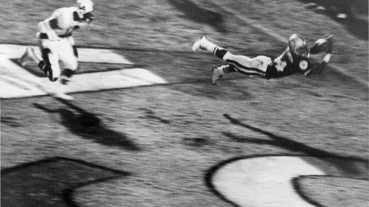 Black-and-white photo of a football player leaping to catch the ball.