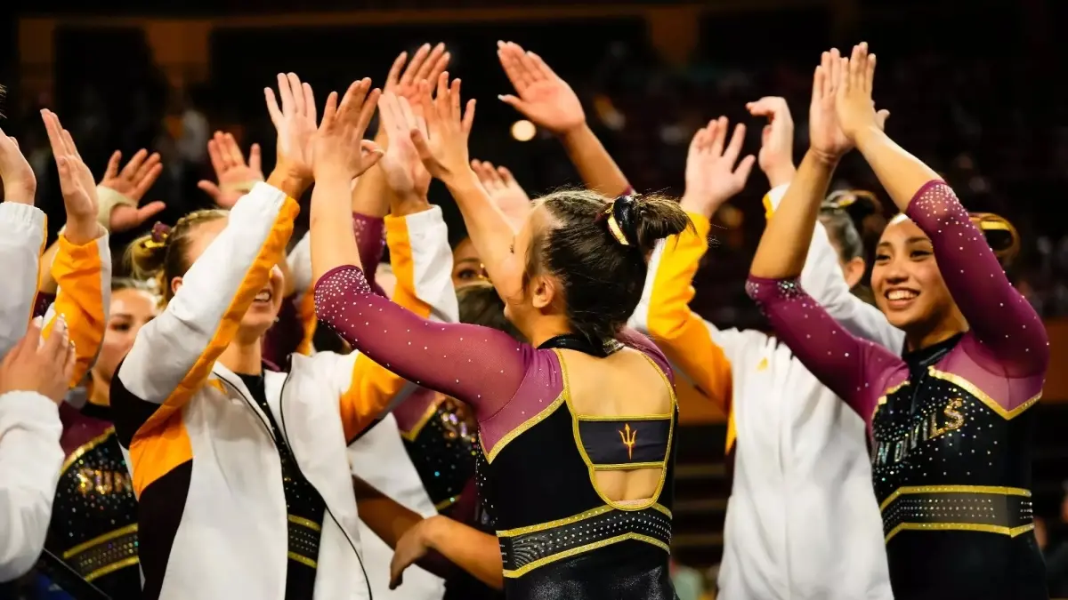 Image from ASU News gymnasts athletes high fiving in a group