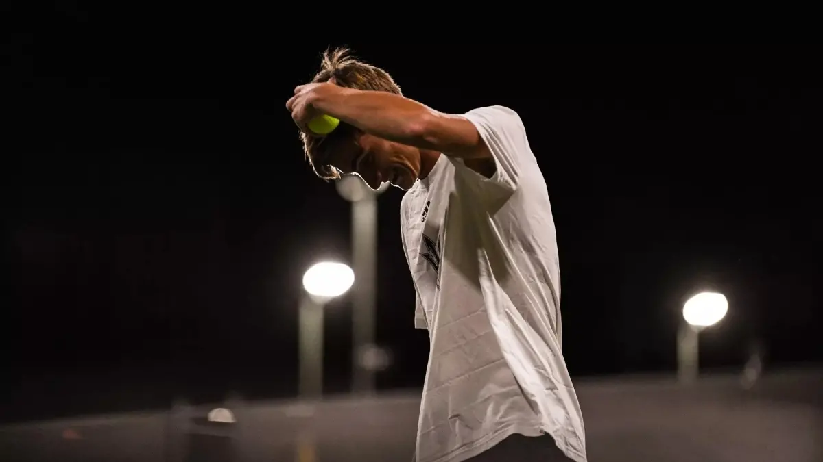 male tennis player looking down and holding tennis ball near head male tennis player looking down and holding tennis ball near head