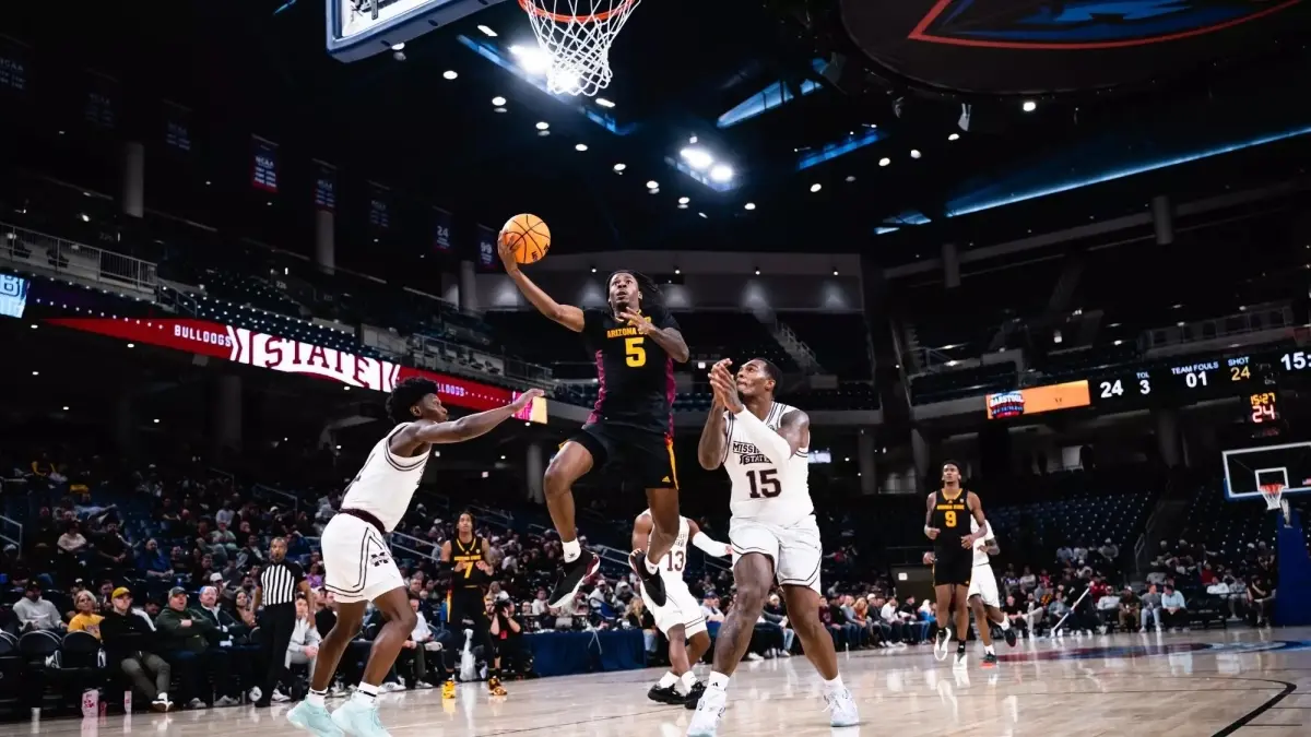 male basketball player jumping with ball while two players play defense