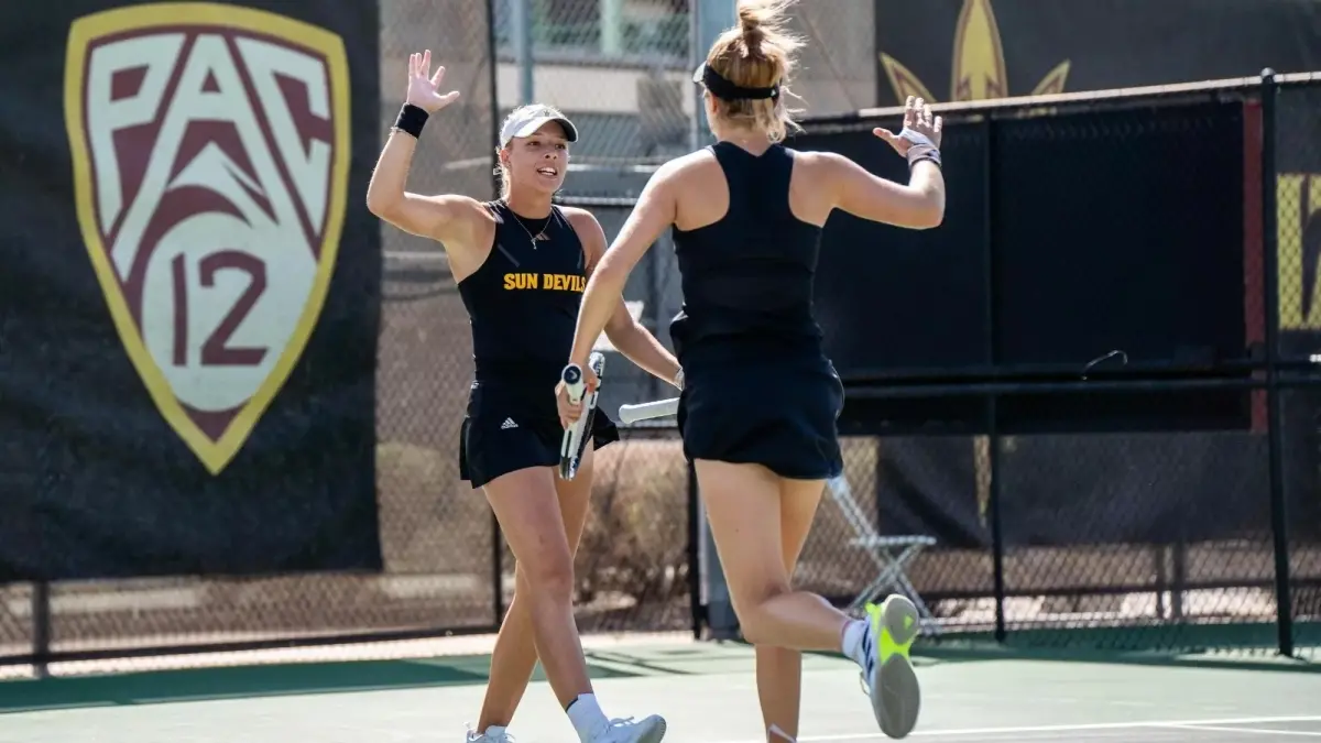 two tennis players on court high fiving two tennis players on court high fiving