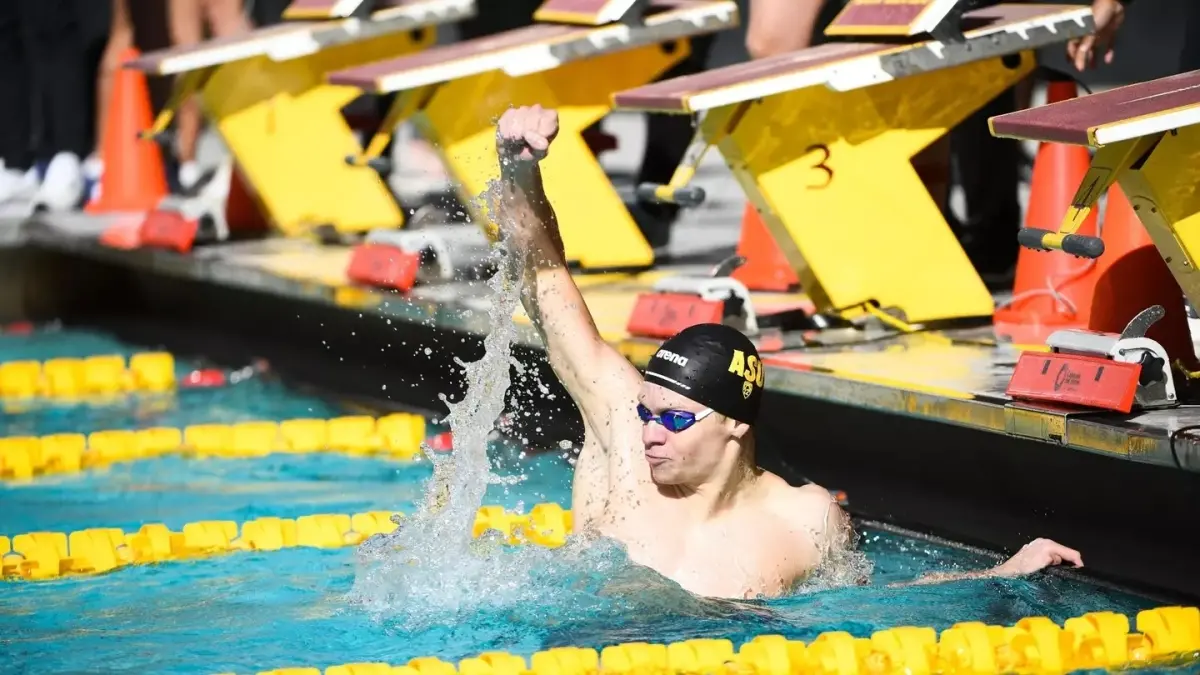 Male swimmer in pool holding his fist up