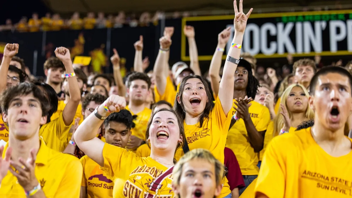 A group of ASU students wearing gold t-shirts cheer at a football game A group of ASU students wearing gold t-shirts cheer at a football game