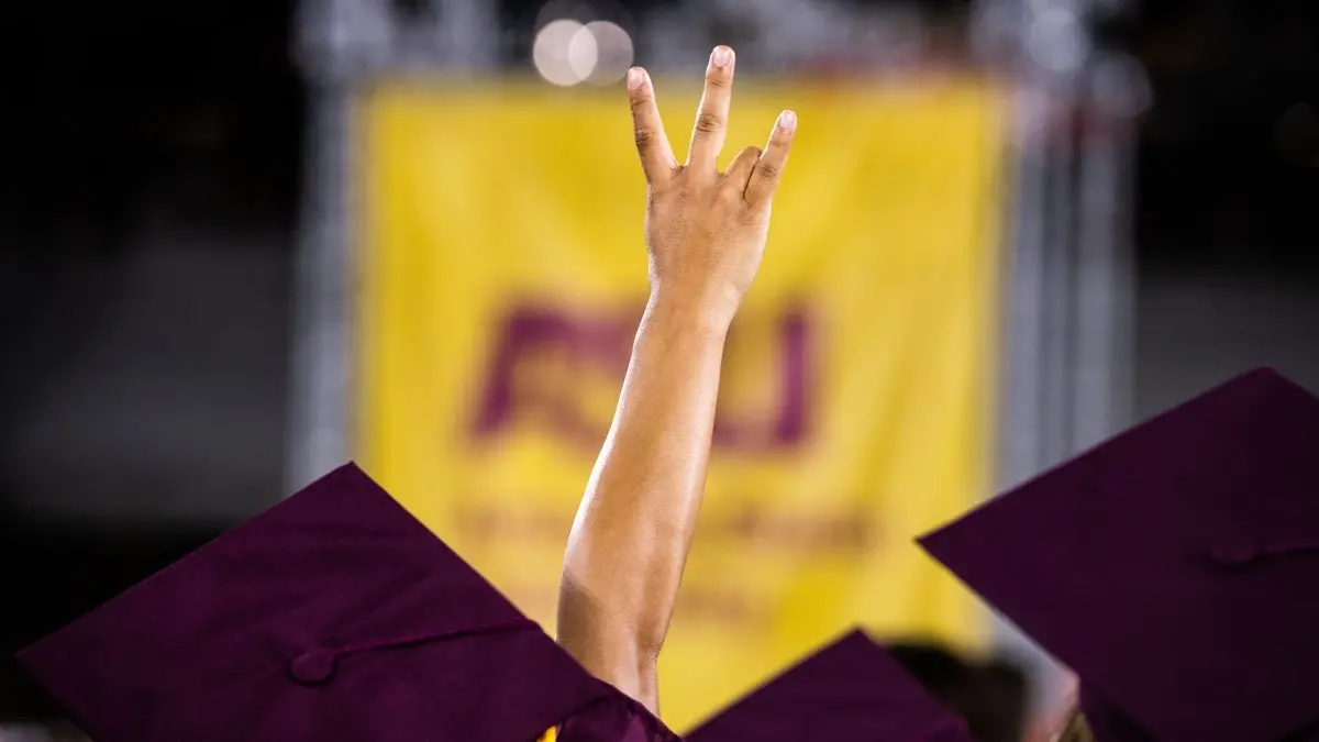 Hand raised, making the ASU pitchfork gesture. Hand raised, making the ASU pitchfork gesture.