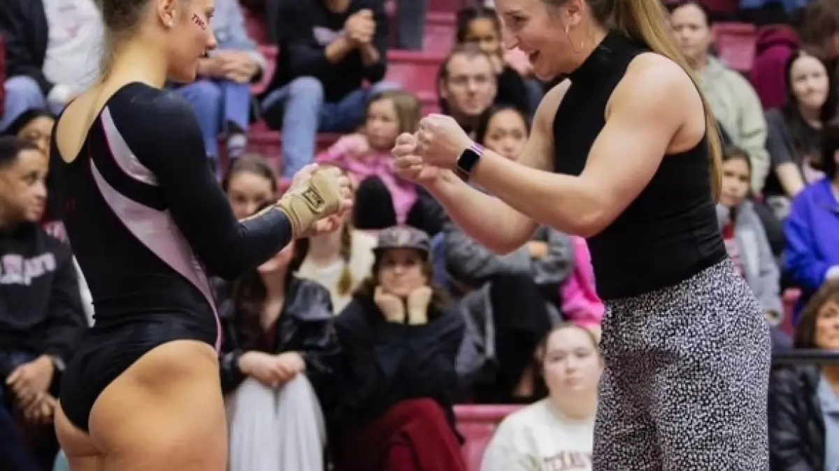 Kristen Harold giving fist bumps to a gymnast at Texas Woman&#039;s University.