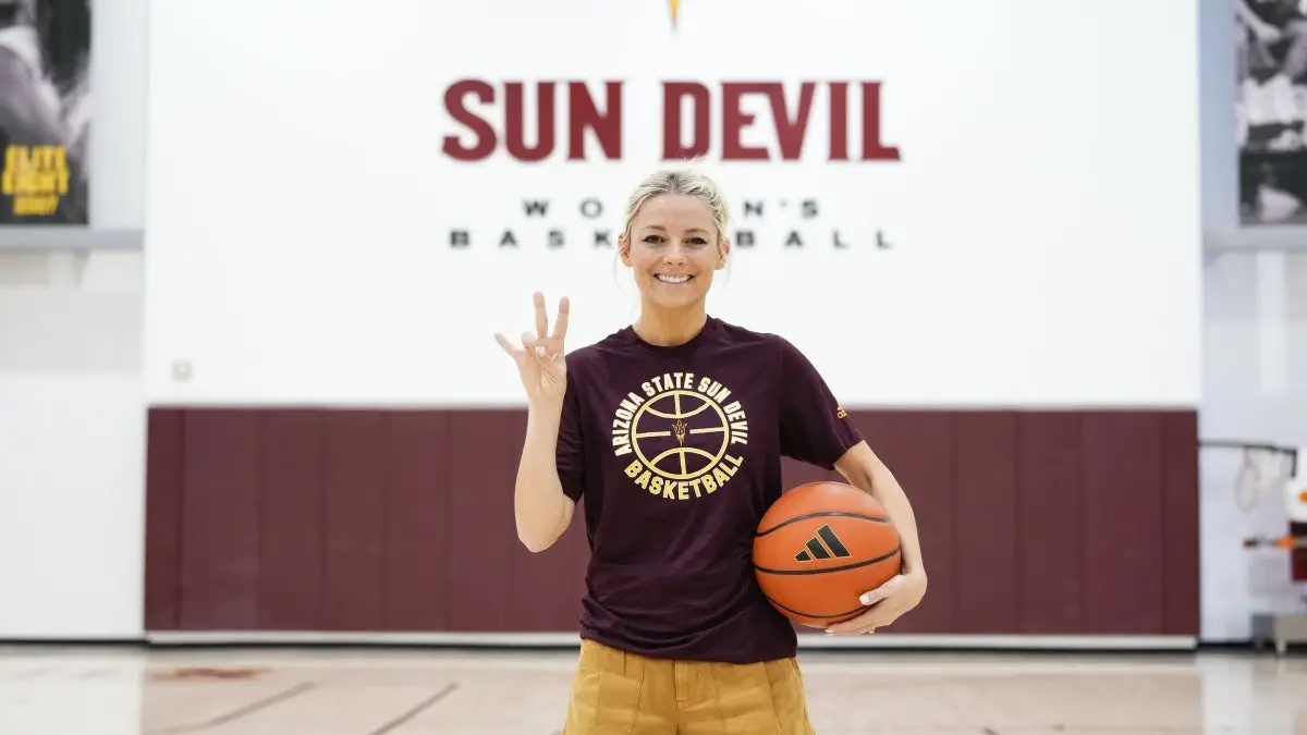Woman in a black T-shirt with blonde hair in a ponytail poses with a basketball. Woman in a black T-shirt with blonde hair in a ponytail poses with a basketball.