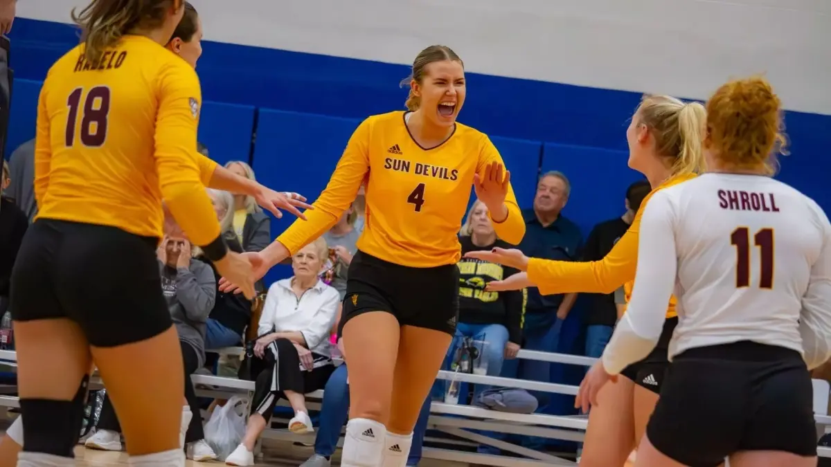 Photo by: Kimberlie Haner<br />
three volleyball player on court celebrating
