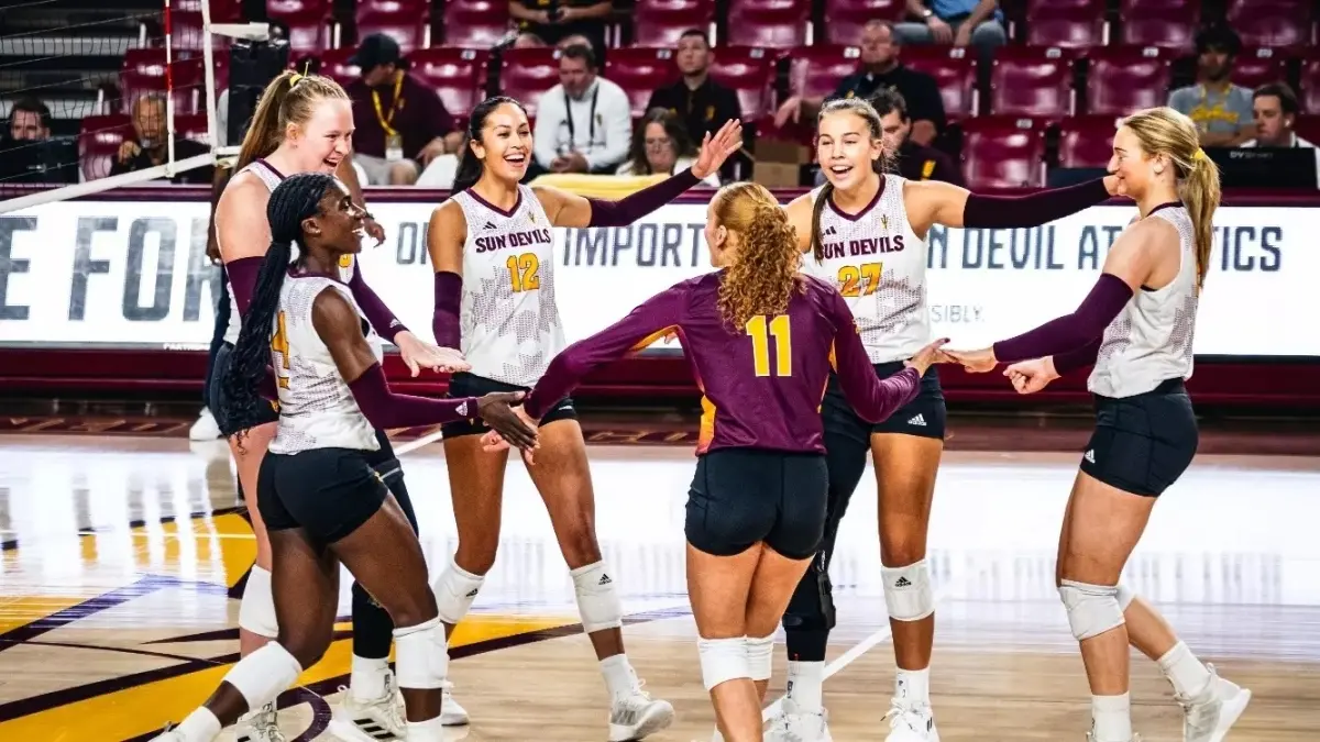 six volleyball players on court celebrating on the court