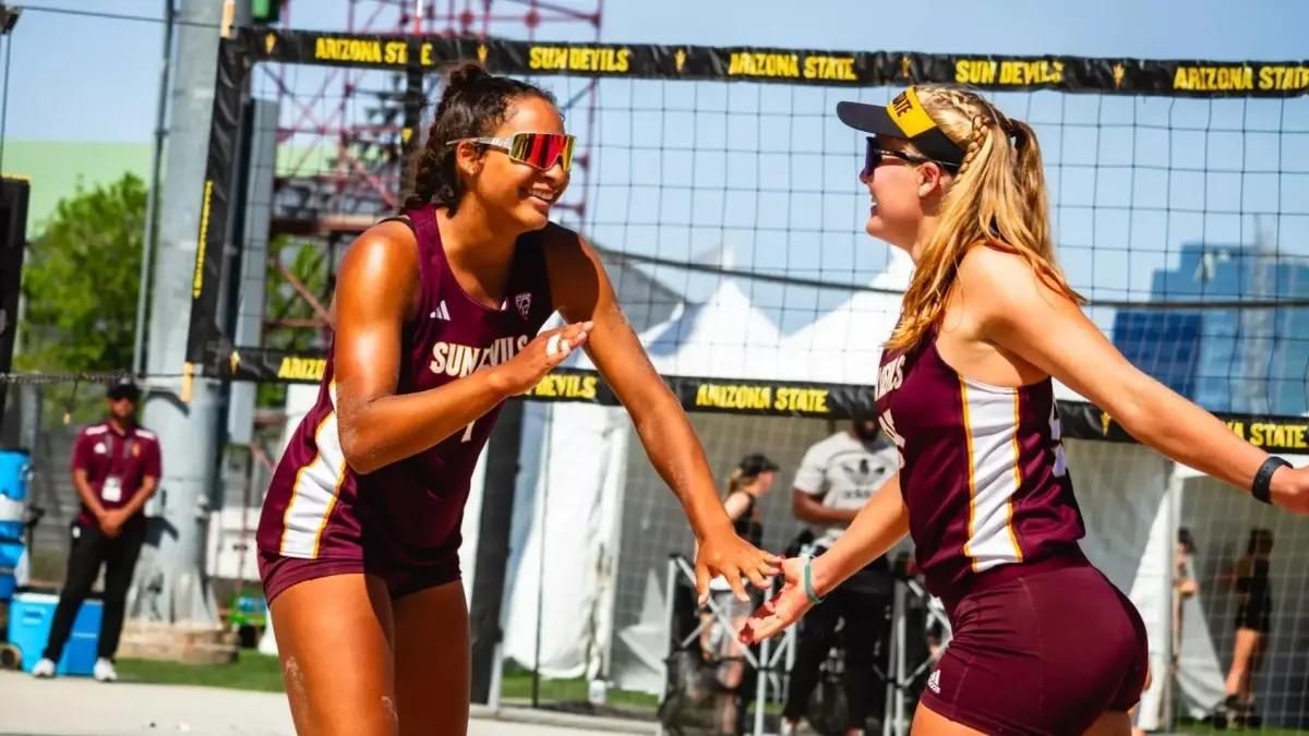 two beach volleyball players high fiving two beach volleyball players high fiving