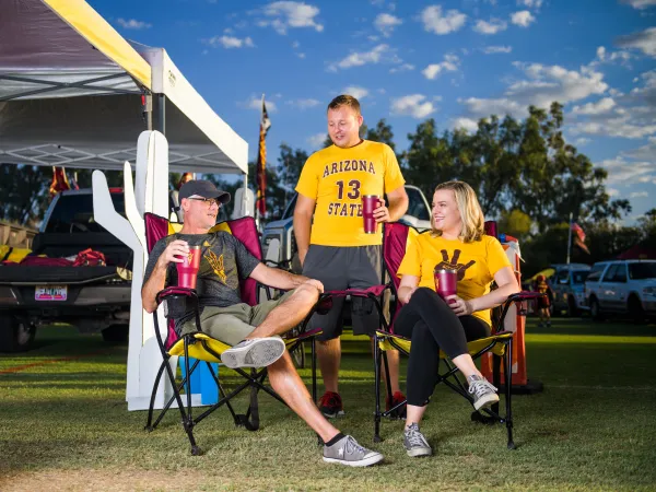 People hanging out in tailgate with their ASU shirts, mugs and flags
