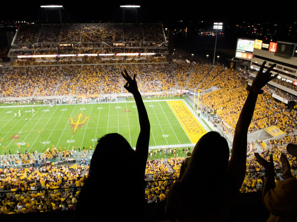 Girl holding pitchfork sign at Sun Devil Football game