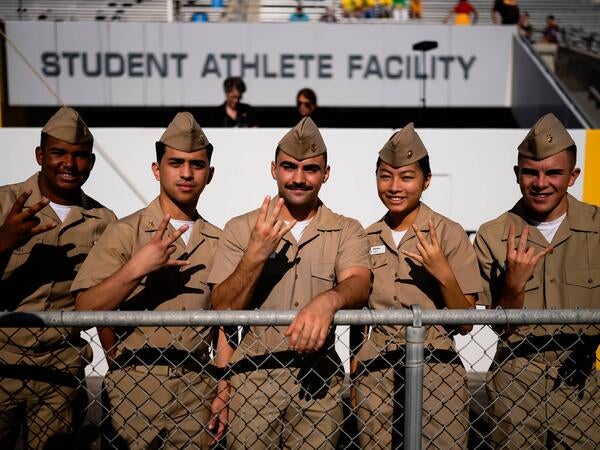 Military men and women with hand pitchfork sign at game